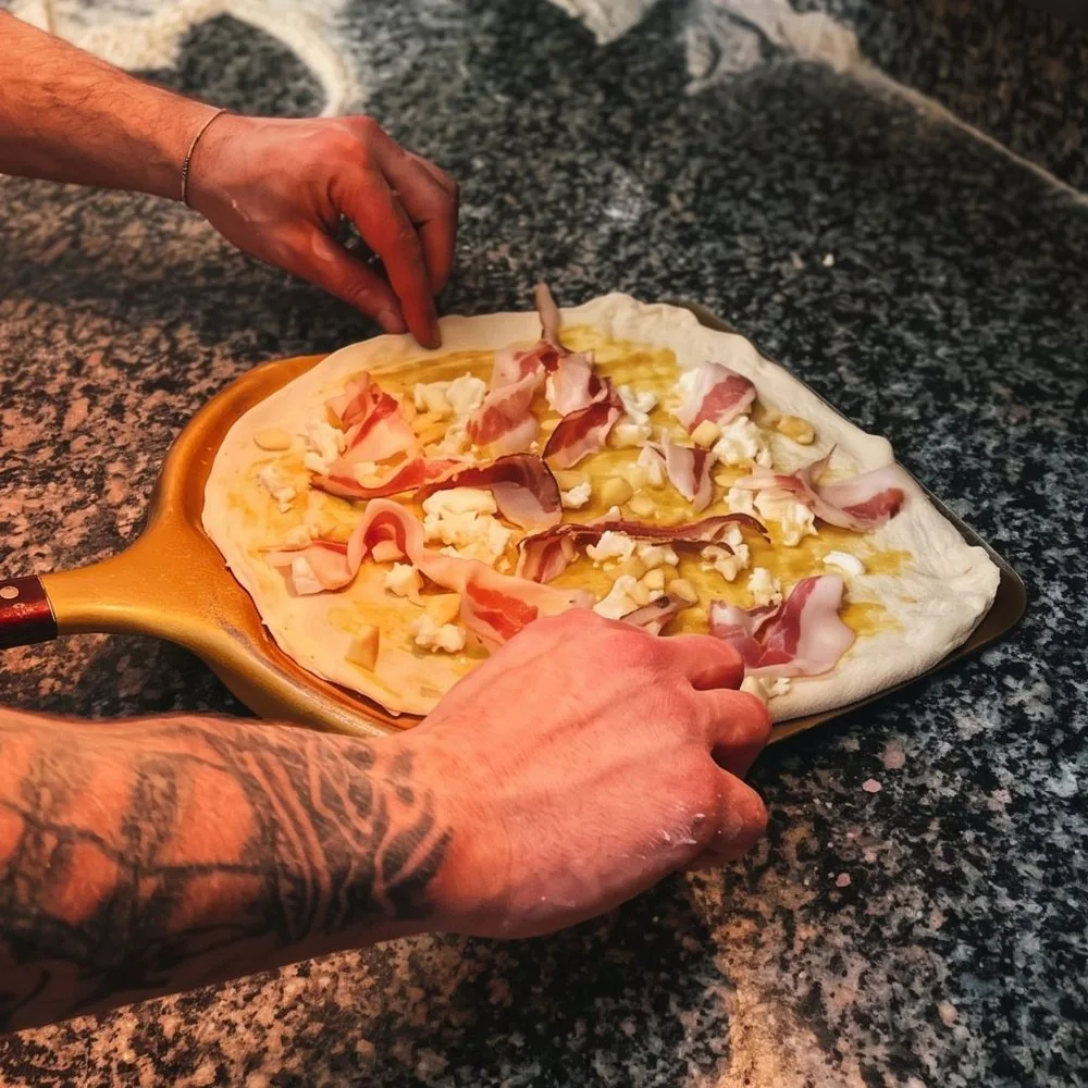 Pizzaiolo che farcisce una pizza sulla pala