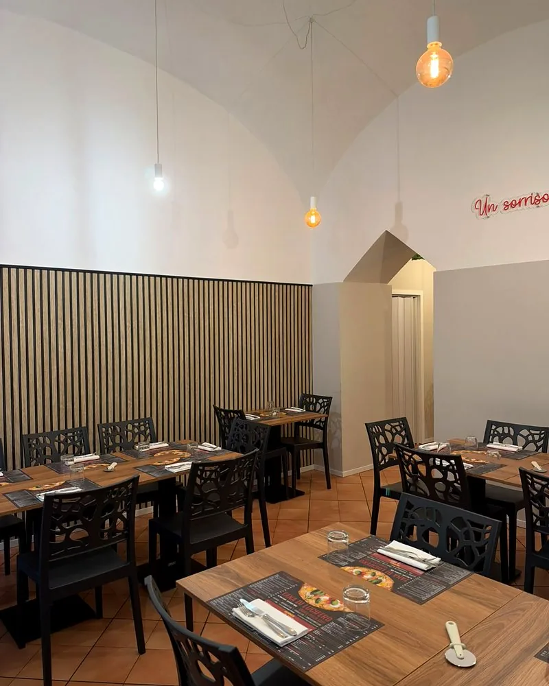 La sala con la parete a listelli di legno e i tavoli apparecchiati
